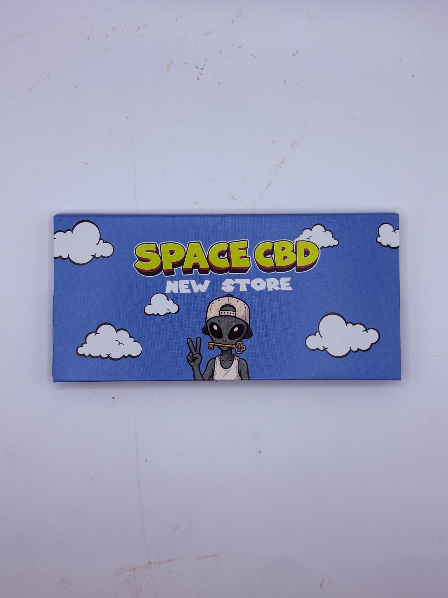 Carnet de feuilles à rouler Space CBD New Store, couverture alien sur fond de ciel bleu